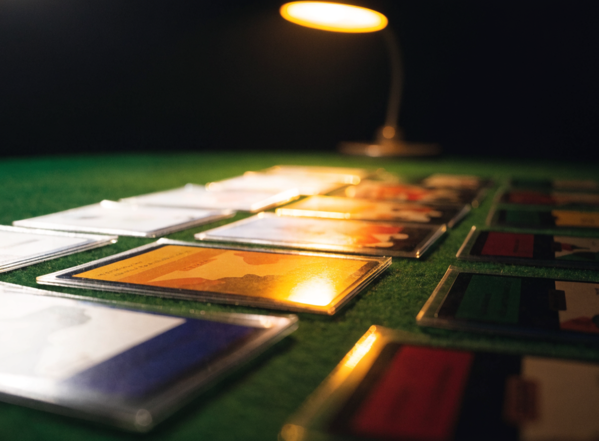 Trading cards in matte sleeves fanned across dark felt under a bench lamp